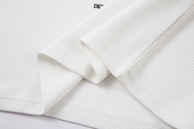Folded white long sleeve tee with layered sleeves and visible textured knit