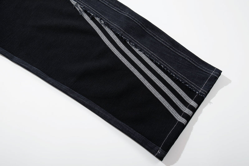 Close-up of the hem showing black jersey side stripe details on dark denim jeans