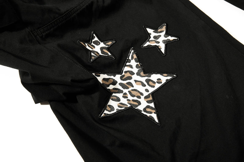 Close-up of black pants leg with leopard star appliqués on the thigh