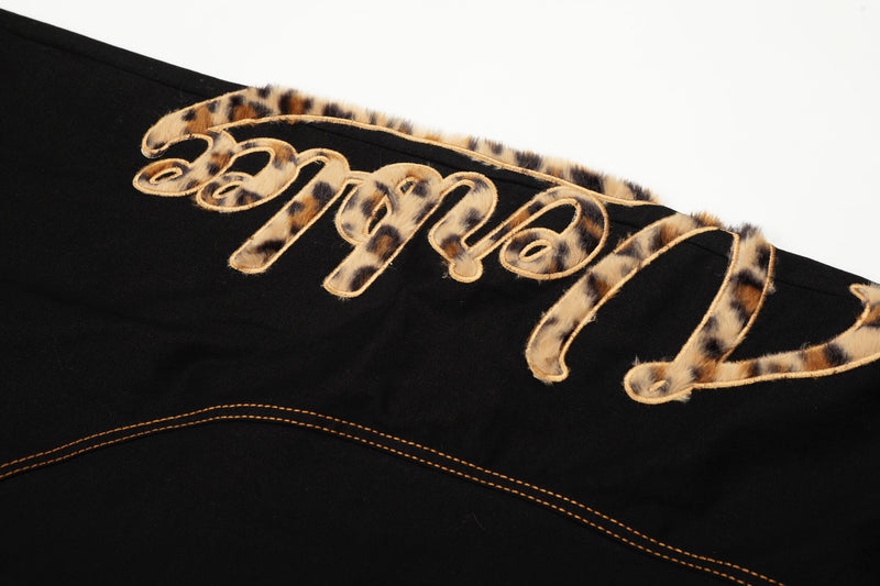 Close-up of leopard patch lettering across the back waistband of black pants