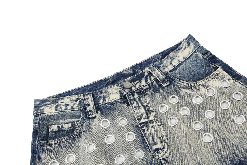 Close-up of front waistband, belt loops, button, and grommet details on washed denim