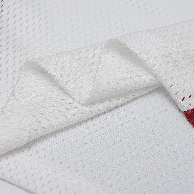 Close-up of white perforated performance jersey fabric with a red trim detail