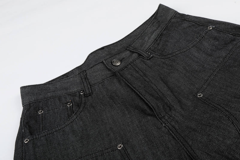 Close-up of front waist and pocket area on black baggy denim shorts with metal rivets