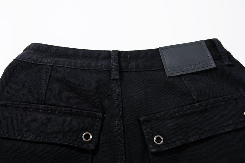 Close-up of black denim waistband with button, belt loops, and logo patch