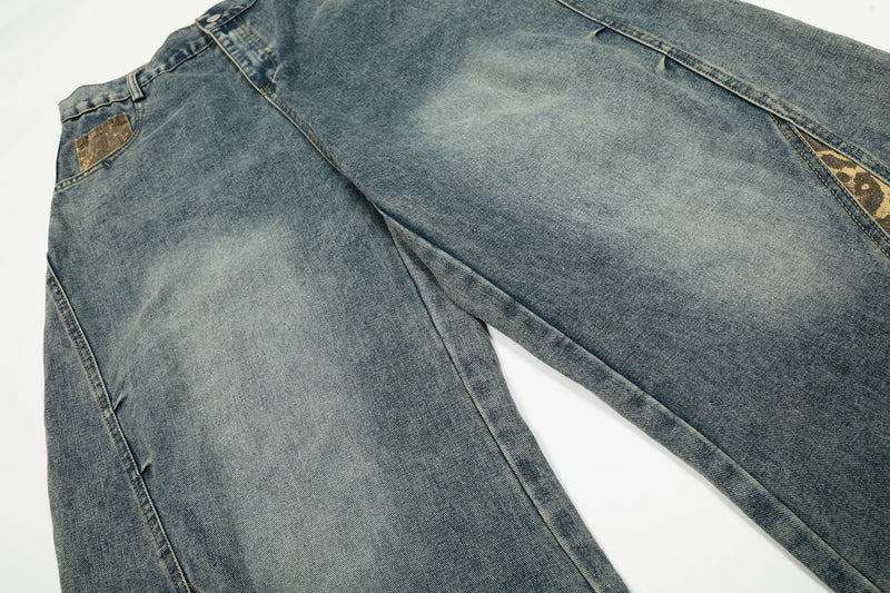 Close-up of blue denim leg panel with faded wash and leopard-print inset