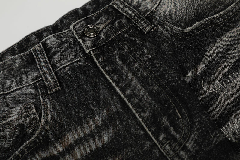 Close-up of front waistband and button on black distressed denim pants