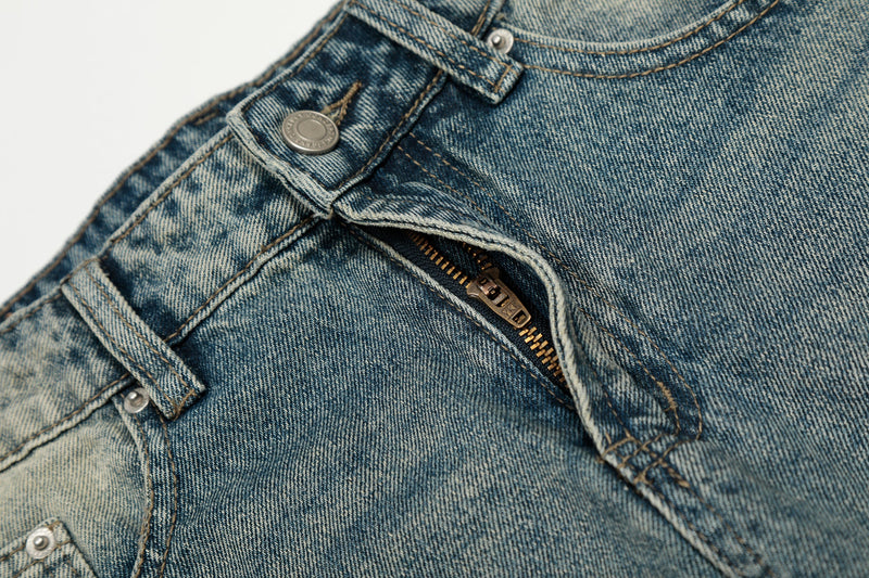 Close-up of front fly area on faded blue jeans with metal zipper and button closure