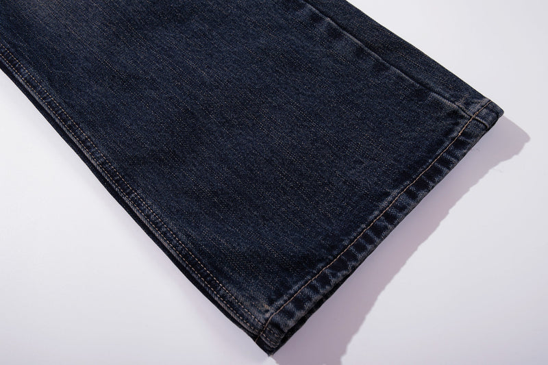 Close-up of the hem on dark wash jeans with clean stitched cuff