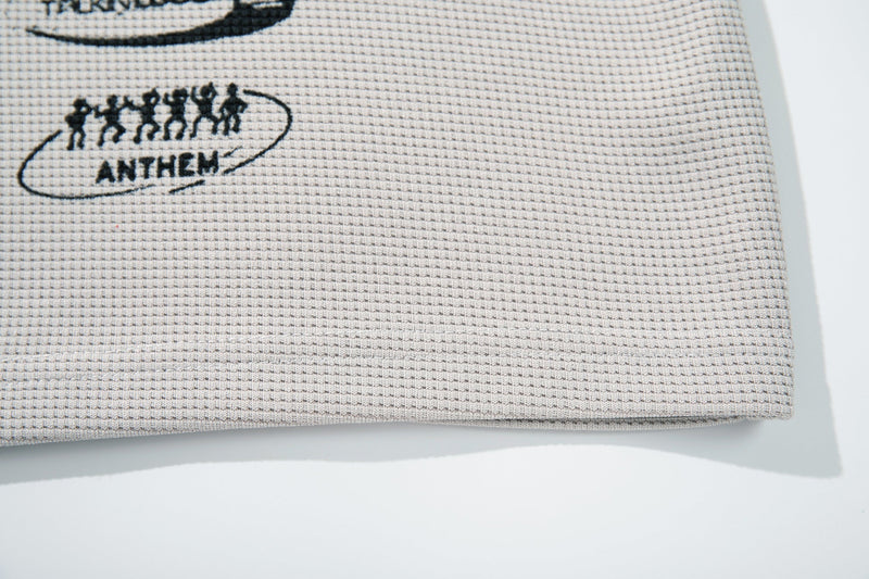 Close-up of beige textured T-shirt fabric with a black punk-style graphic and anthem text detail