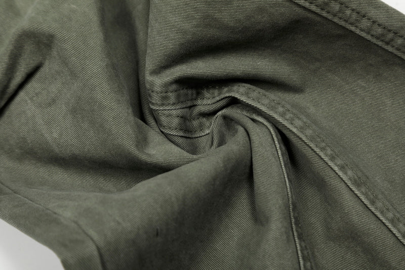 Close-up of olive green pants leg seam and fabric drape