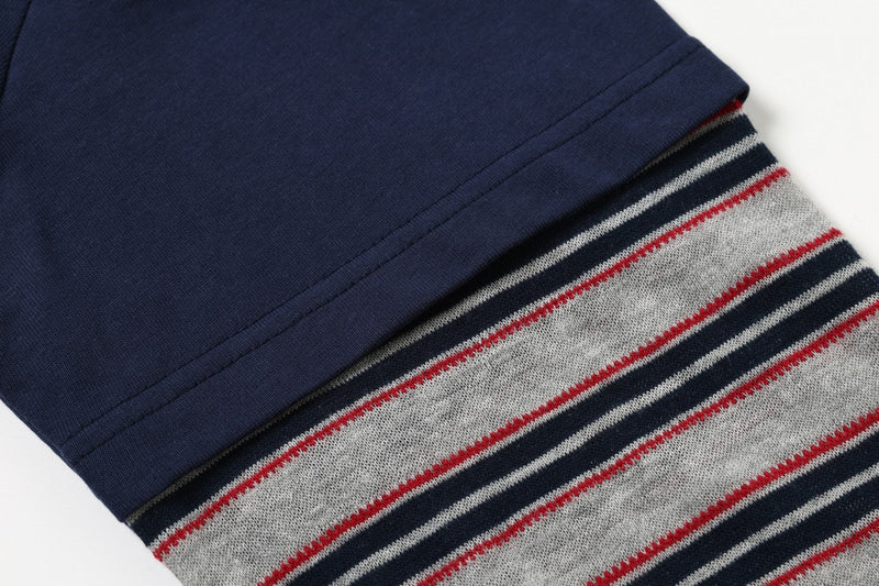 Close-up of navy sleeve seam meeting a gray, red, and black striped cuff