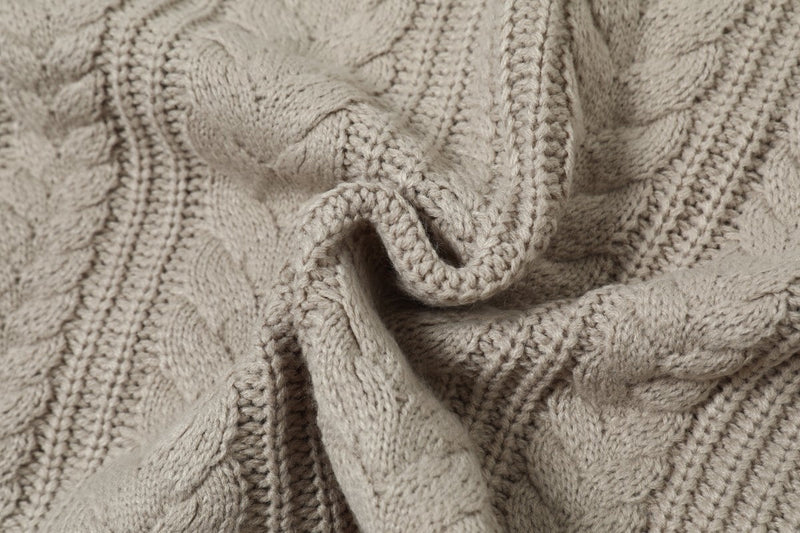 Close-up of beige cable knit sweater fabric gathered in folds