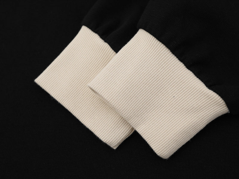 Close-up of cream ribbed cuff on black sweatshirt sleeve