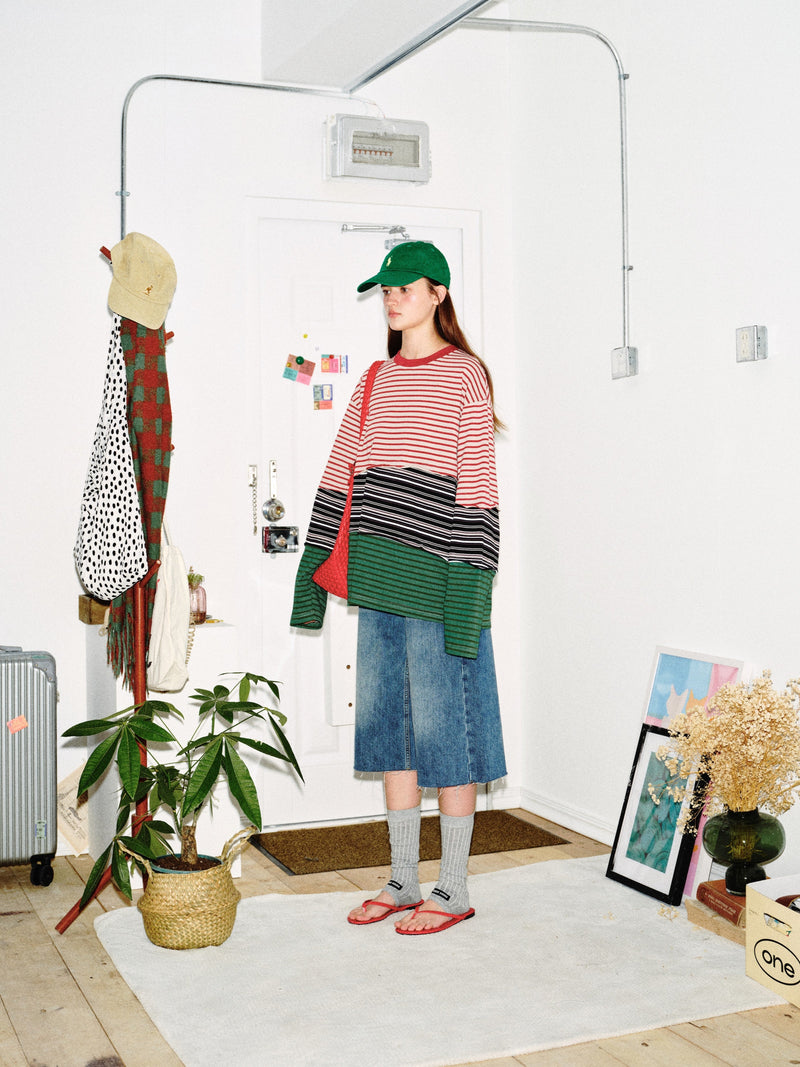 Side view of model wearing color-block striped long sleeve tee with red, black, and green stripes