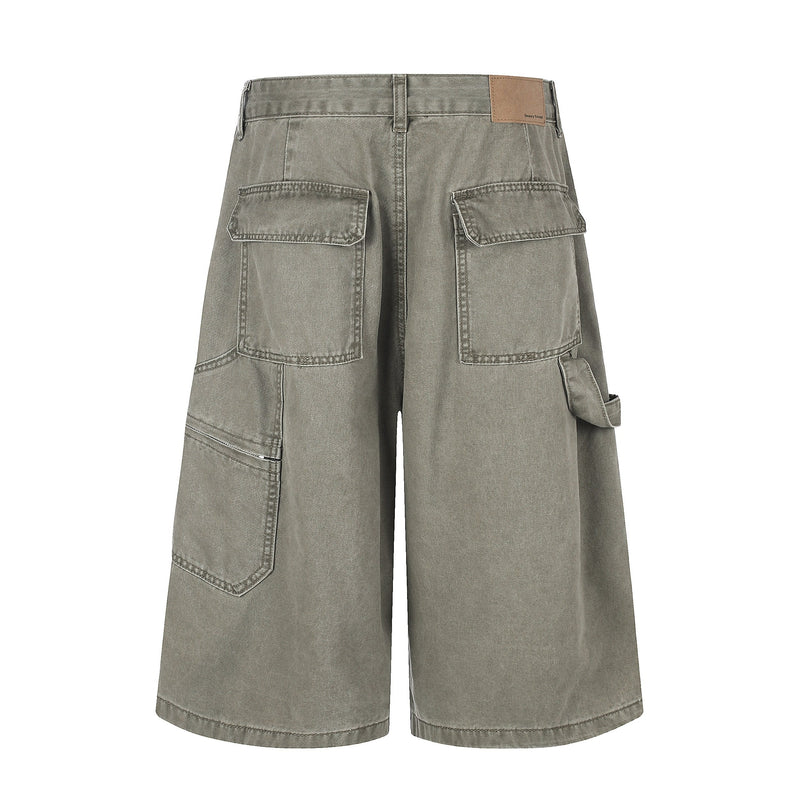 Back view of gray cargo shorts with flap back pockets and a tan logo patch at the waistband