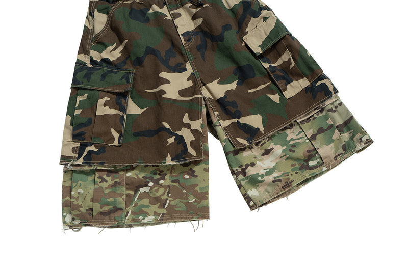 Partial side view of camouflage cargo shorts with flap pockets and frayed hems