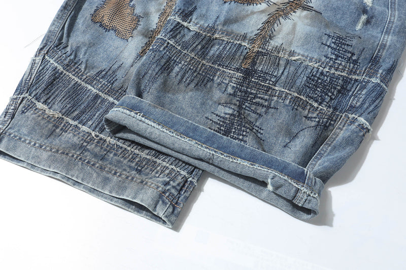 Close-up of folded hem and patchwork stitching on distressed blue jeans