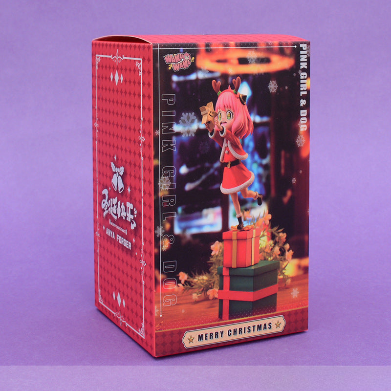 The red box features a festive cartoon of a pink-haired girl resembling the Anya Forger Christmas PVC Figure - 18cm Holiday Edition by Spy × Family. Dressed in holiday attire, she stands on stacked gifts holding a present, capturing the cheerful spirit of &quot;Pink Girl &amp; Dog.