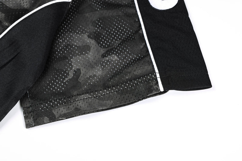 Dark camo mesh athletic jersey hem with white piping and black sleeve on a clean white background
