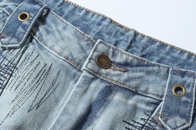 Close-up of waistband button, belt loops, and stitching on distressed blue denim