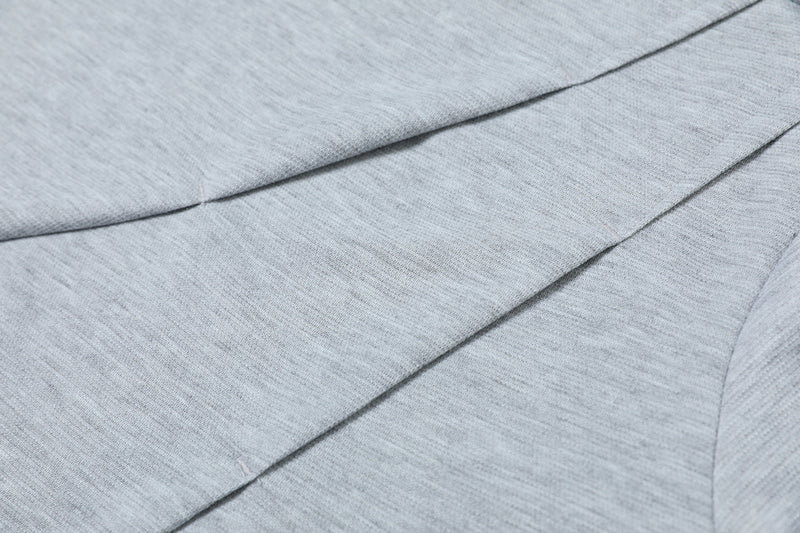 Close-up of light gray oversized tee fabric with asymmetric seam detailing and soft textured knit texture