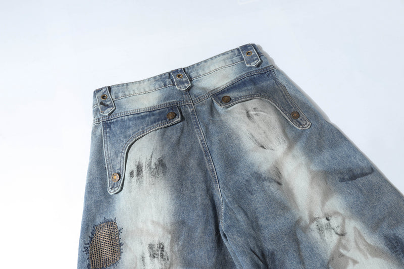 Top back waistband close-up of faded blue patchwork jeans with back pockets