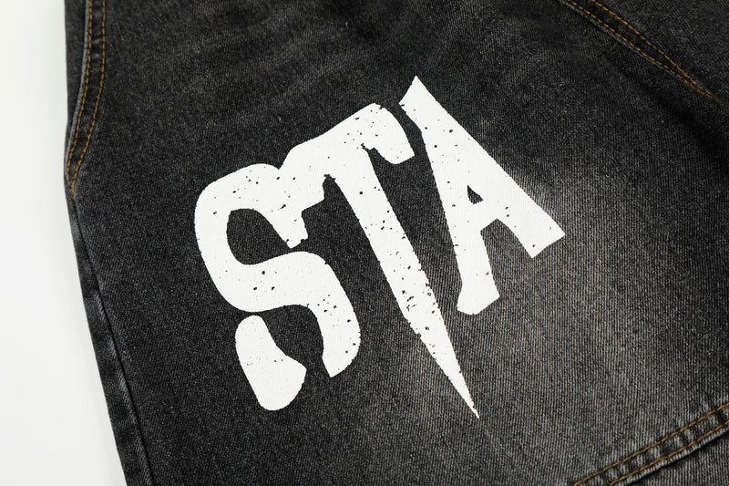 Close-up of front leg showing white star graphic on black washed denim