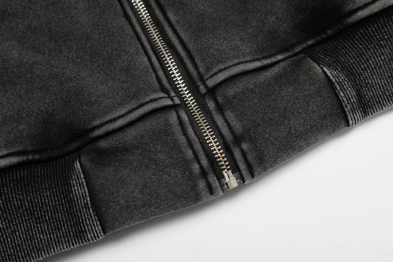 Close-up of black hoodie lower front with zipper and ribbed hem