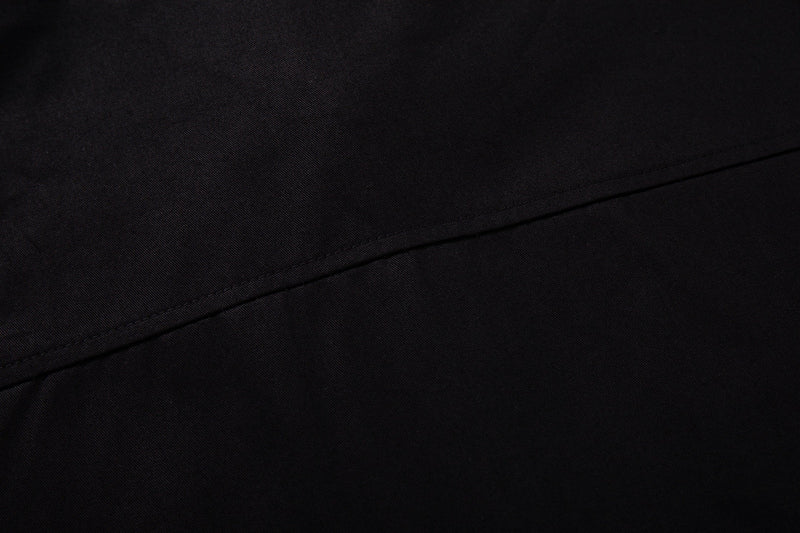 Close-up of black fabric with diagonal seam detail on a Seakoff graphic button-up streetwear shirt