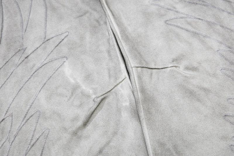 Close-up of light gray jeans leg with outlined embroidery detail