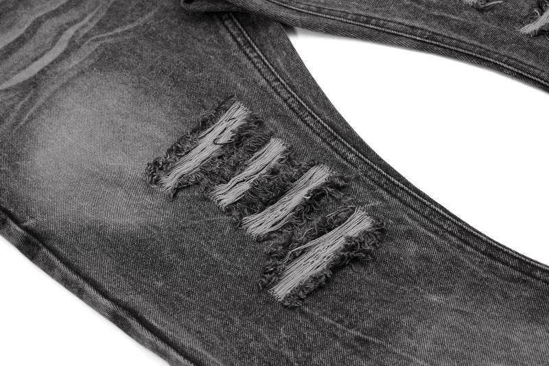 Close-up of distressed thigh rip on denim jeans with frayed threads