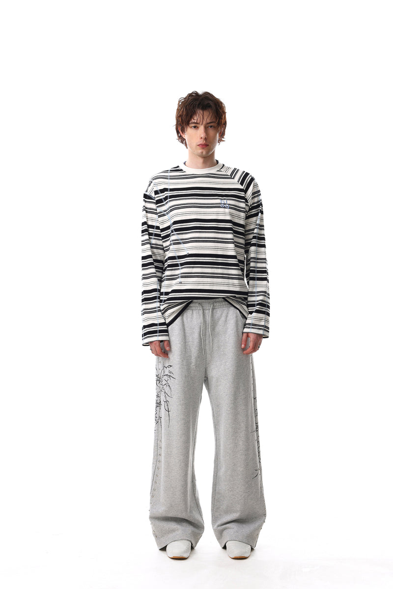 Front view of black and white striped long sleeve crewneck tee worn with gray pants