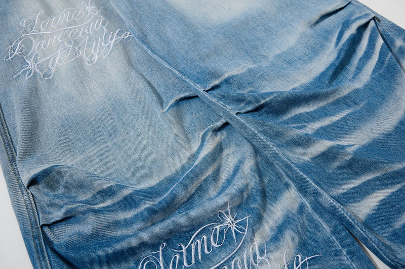 Close-up of white script embroidery on faded blue denim