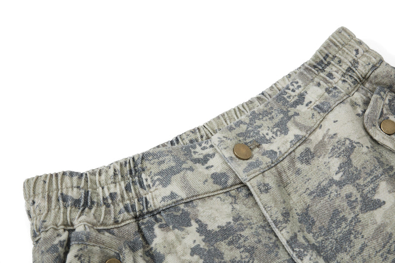 Close-up of elastic waistband on camo cargo pants with button closure and gathered fabric