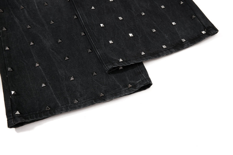 Cuffed hem of black studded wide-leg jeans with silver pyramid studs