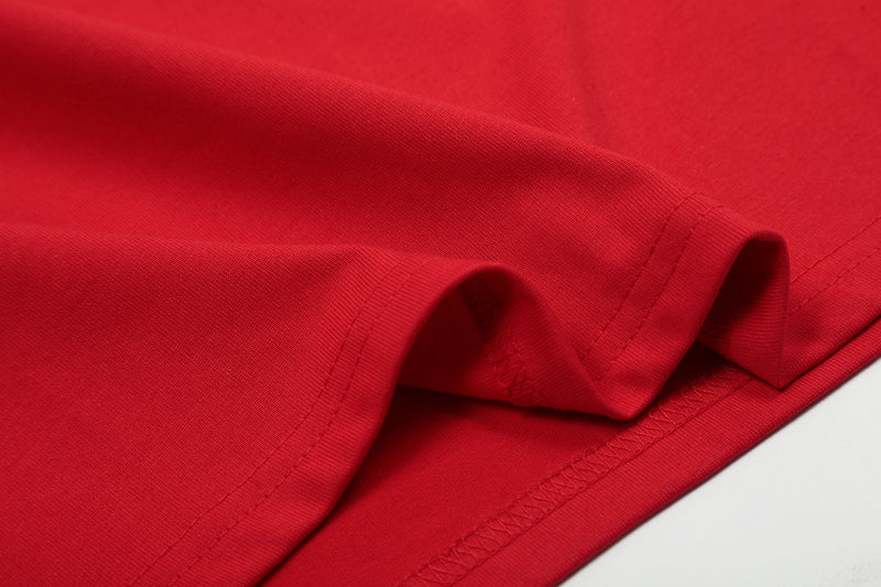Close-up of a red cotton raglan T-shirt hem with visible stitching and folded sleeve details