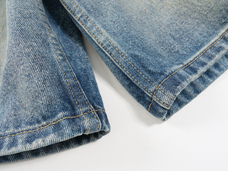 Close-up of hem and side seam on faded wide-leg denim shorts