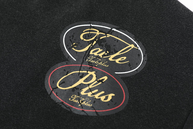 Close-up of two oval logo patches on black hoodie, one outlined in white and one in red