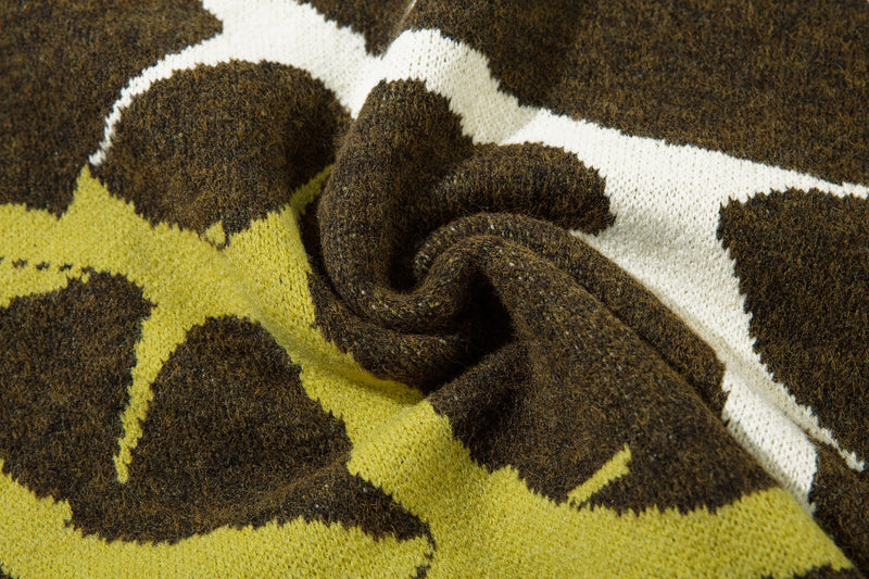 Close-up of crumpled knit sweater fabric with olive, yellow and white abstract camo pattern