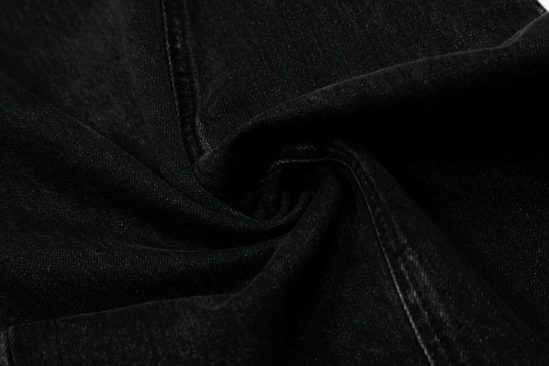 Close-up of black denim fabric showing soft folds and stitched seam detail
