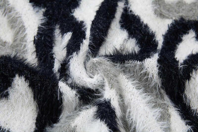 Close-up of black and white faux-fur hoodie fabric with abstract flame stripes