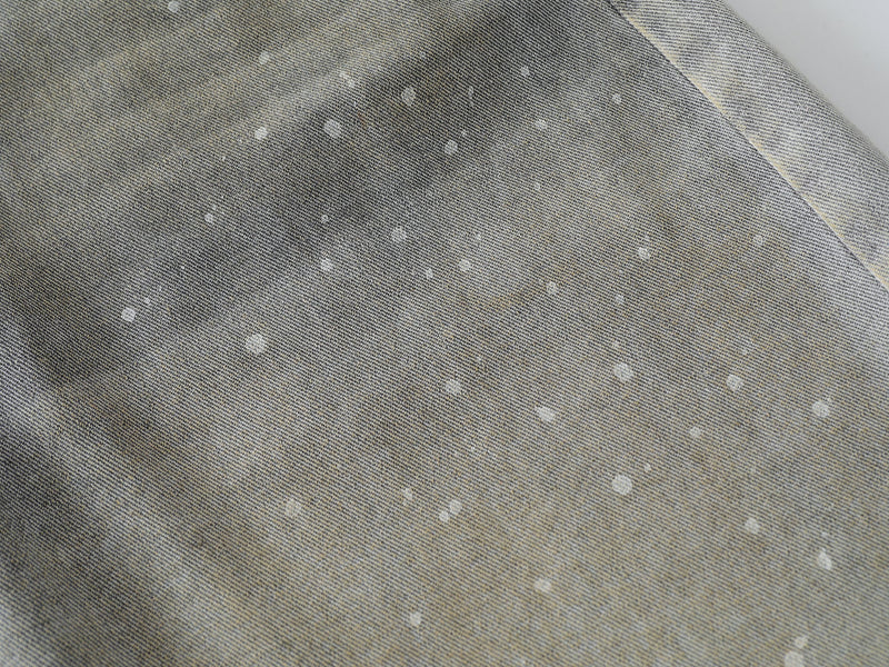 Close-up of grey wash denim fabric with white speckled fade pattern