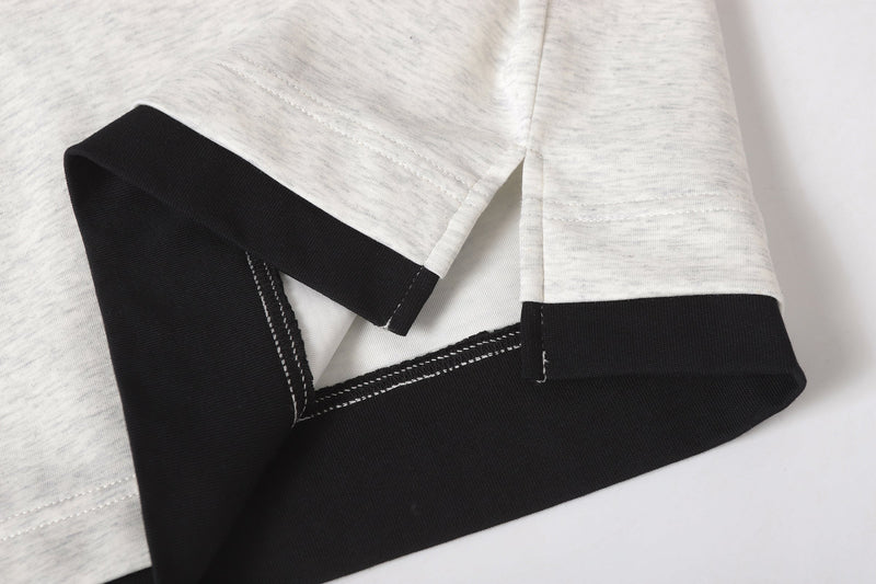 Close-up of sleeve hem showing light gray outer sleeve over black underlayer with stitched edges