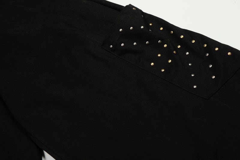 Close-up of black cargo pocket flap with silver and gold studs