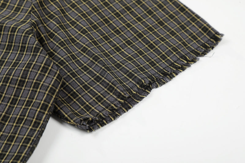 Black and yellow plaid shirt with raw frayed hem and distressed texture close-up on white background