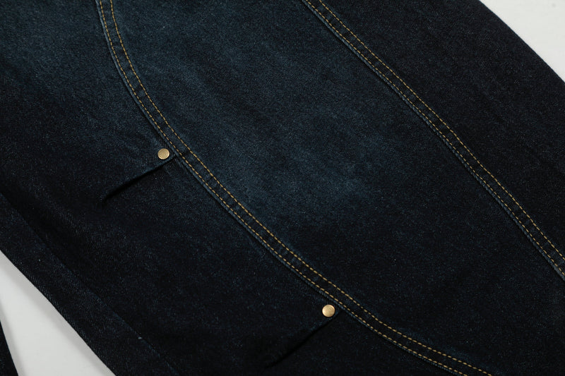 Close-up of leg panel seam and snap detail on dark wash denim pants