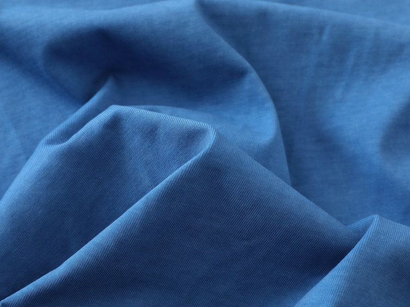 Close-up of blue cotton T-shirt fabric with soft folds and a smooth knit texture