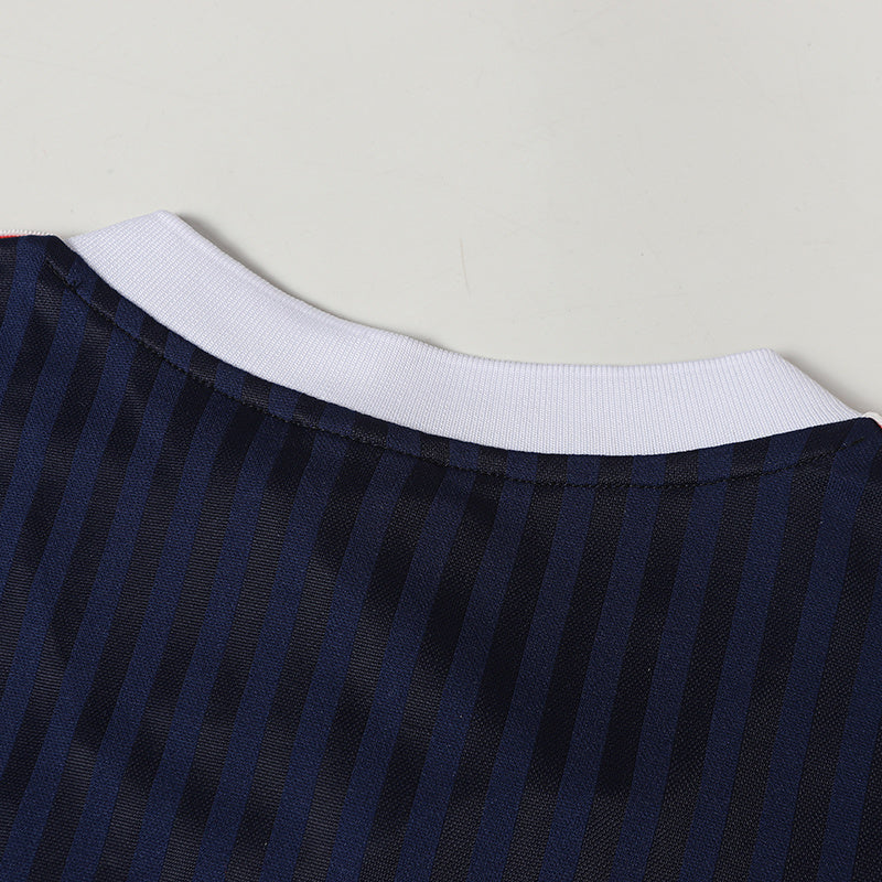 Close-up of a navy striped soccer jersey with a white ribbed crew neck and textured performance fabric