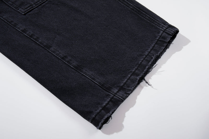 Close-up of the frayed hem on washed black wide-leg jeans