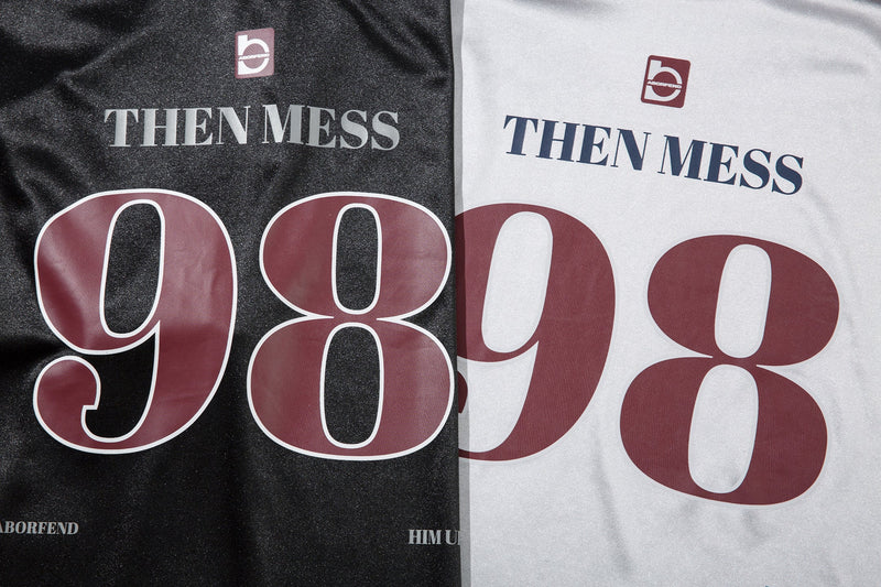 Close-up of black and white jersey tees showing THEN MESS 98 print